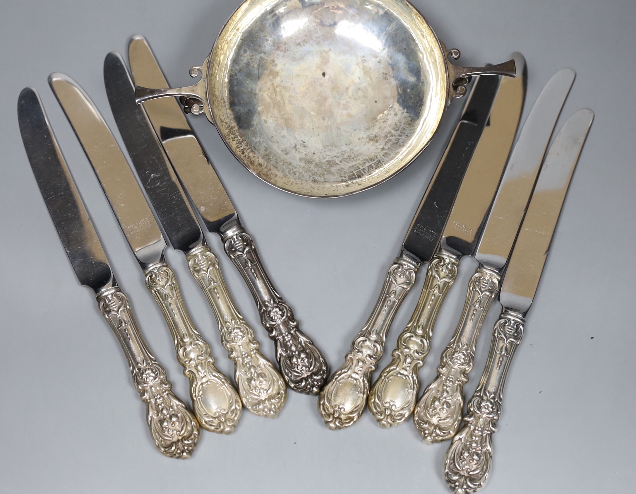 A George V silver porringer, with planished decoration, London 1910, 22cm, 247 grams and eight Reed and Barton table knives with plated handles